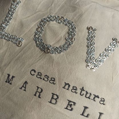 Détail des motifs du grand sac cabas de plage en toile de coton beige grisé, inscription love métallisé, lanières et  renforts en cuir, modèle unique et éco-responsable 